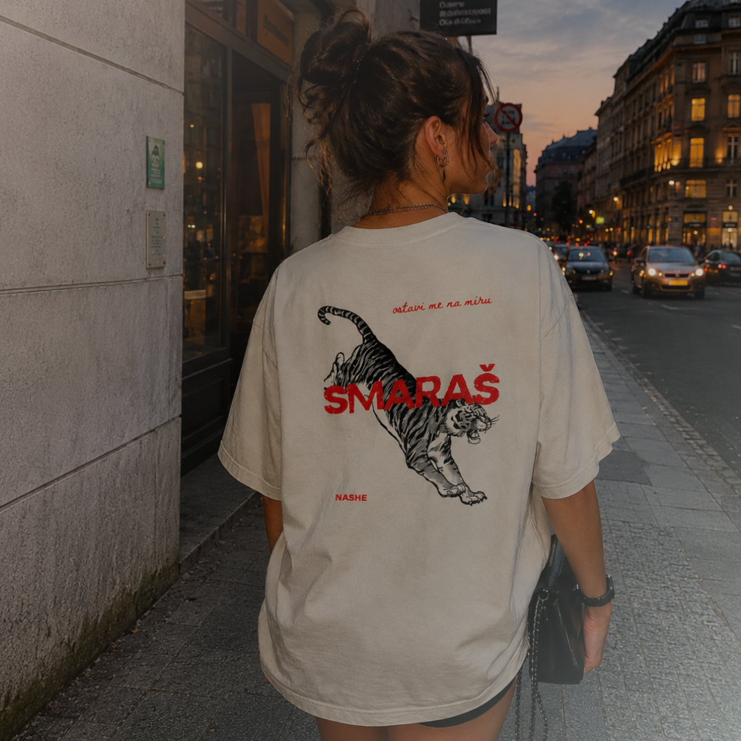 Woman wearing an oversized NASHE shirt on a Balkan city street at dusk